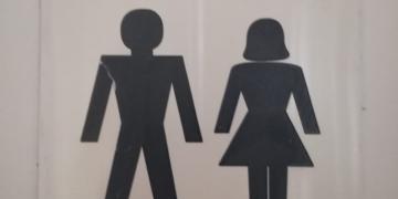 Sign with two classic pictograms for women's and men's toilet, black on white.