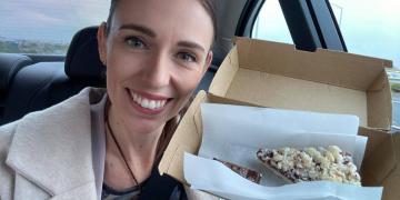 Jacinda Ardern smiling in the camera, posing with a piece of pie.