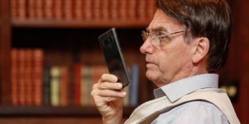 Bolsonaro holding a cell phone with his right hand in front of his face