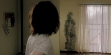 Pulse's main character Kudo Michi looks back at a human-shaped ash stain on the wall